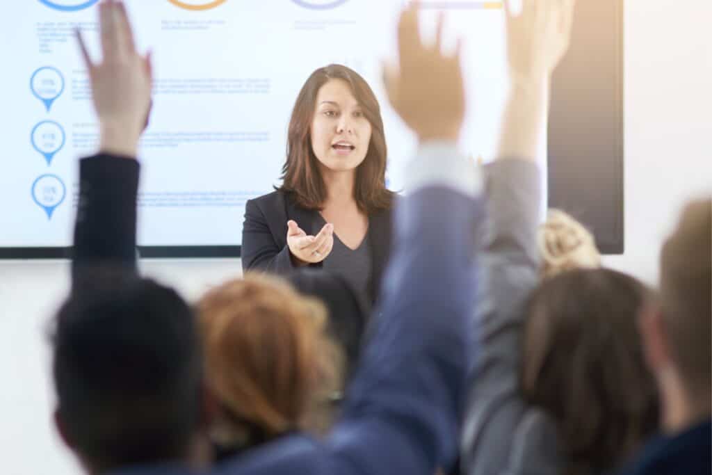 diversity in edtech blog banner. A teacher stands infront of a screen teaching a class. Two of the pupils have their hands raised.
